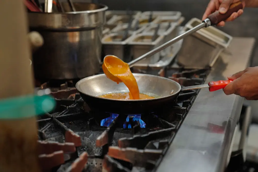 Curry ladled into a pan over the flame