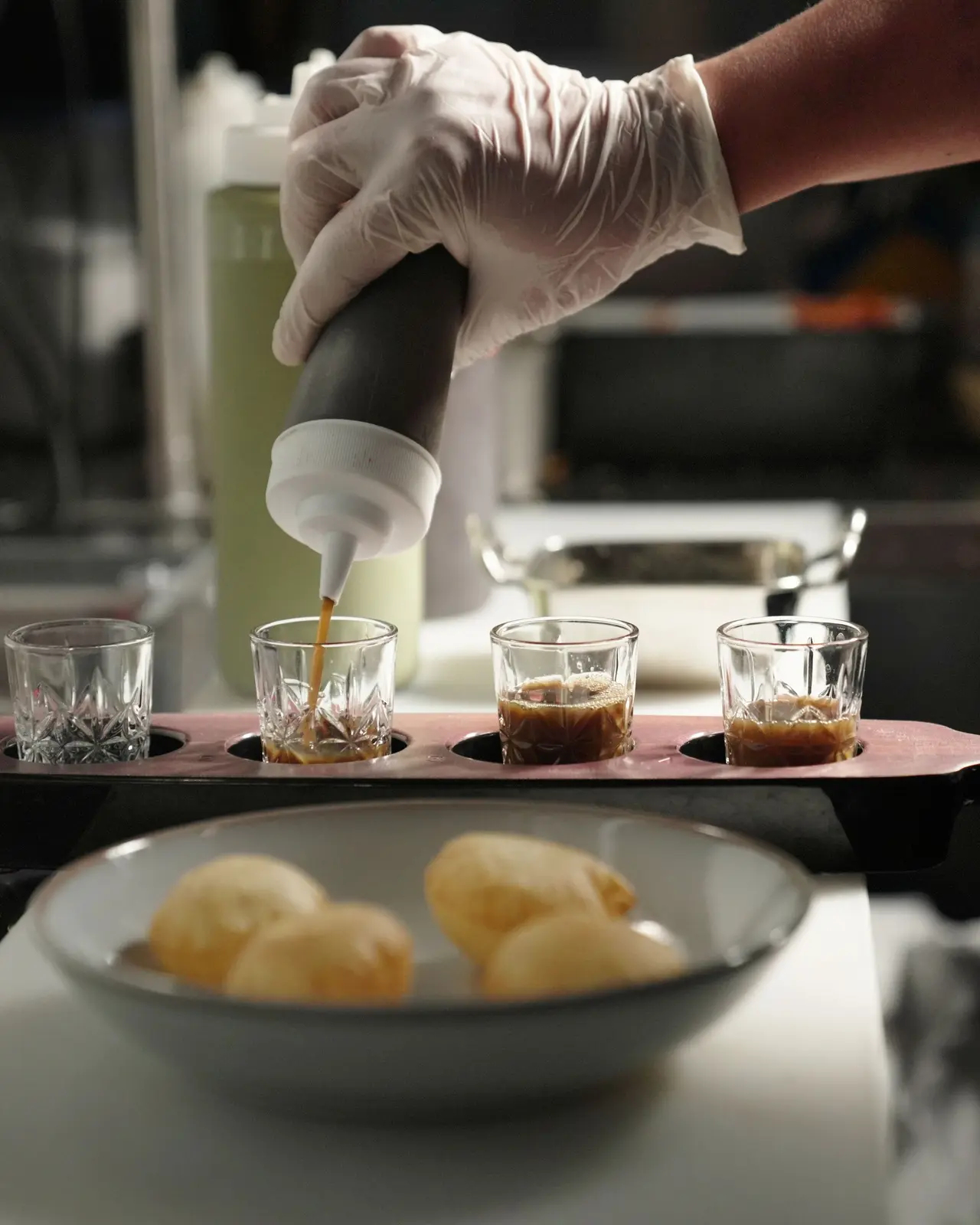 Spiced water poured into shot glasses, the puris waiting in a bowl