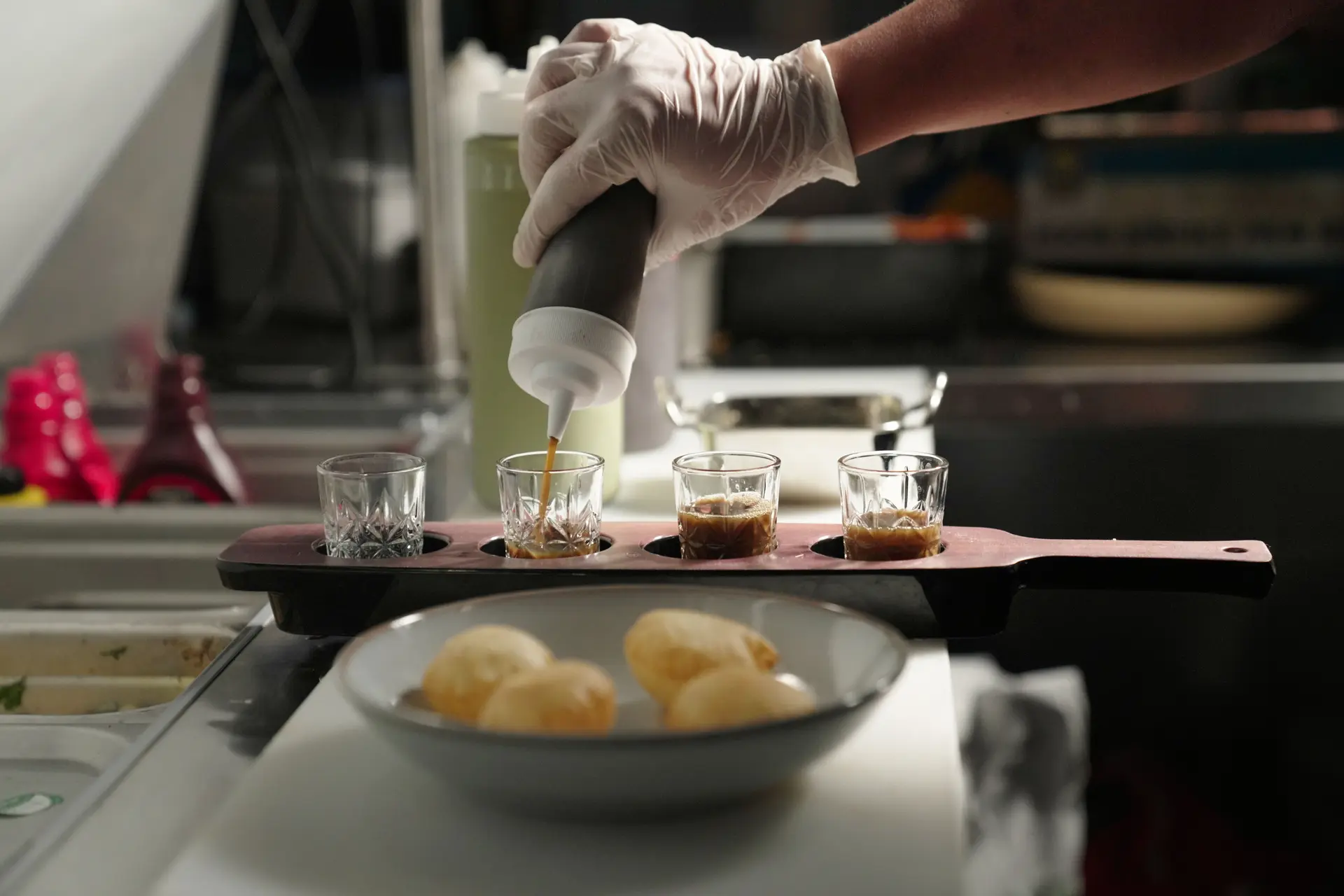 Pani puri: shots poured on a wooden paddle beside a bowl of puris