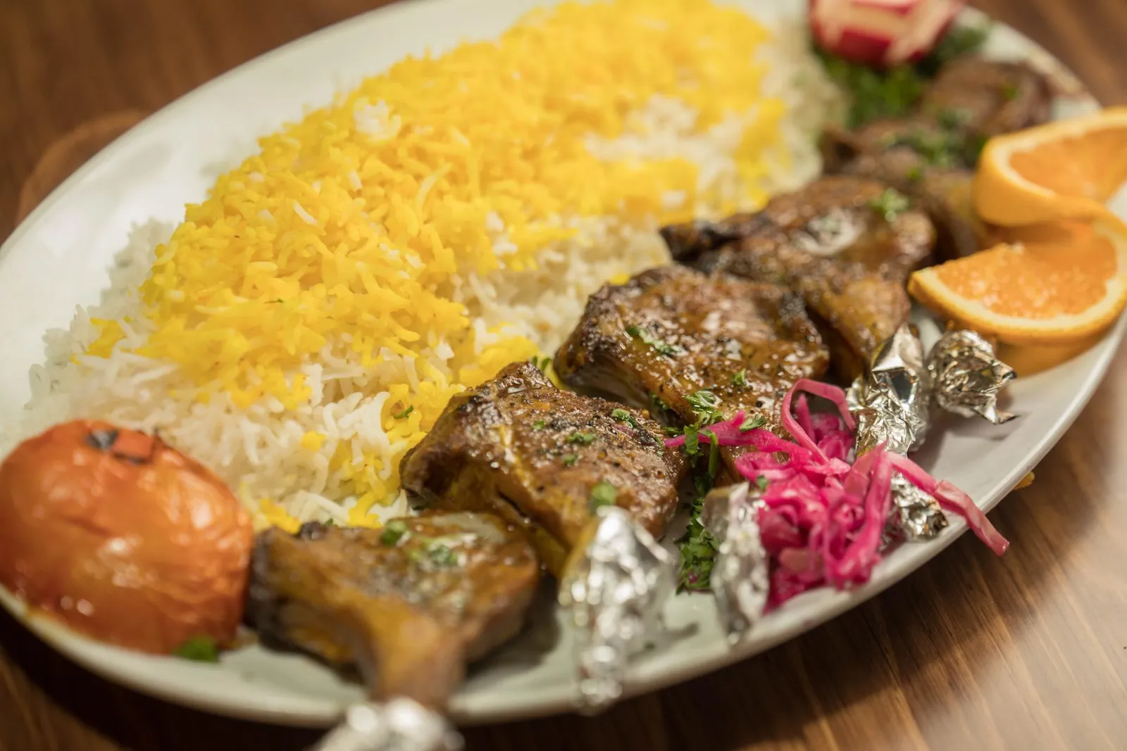 Rack of lamb with saffron rice, a grilled tomato and orange slices