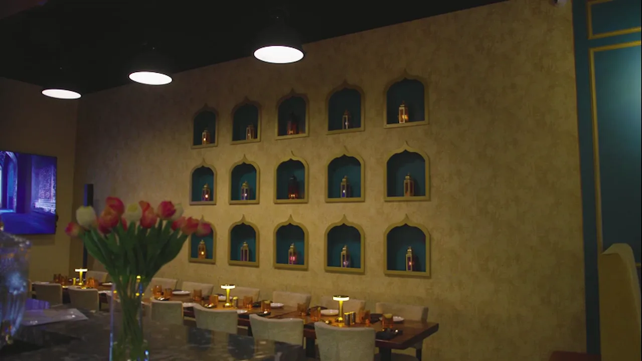 The dining room at Kebab & Kurry, lamps glowing in the plaster niches
