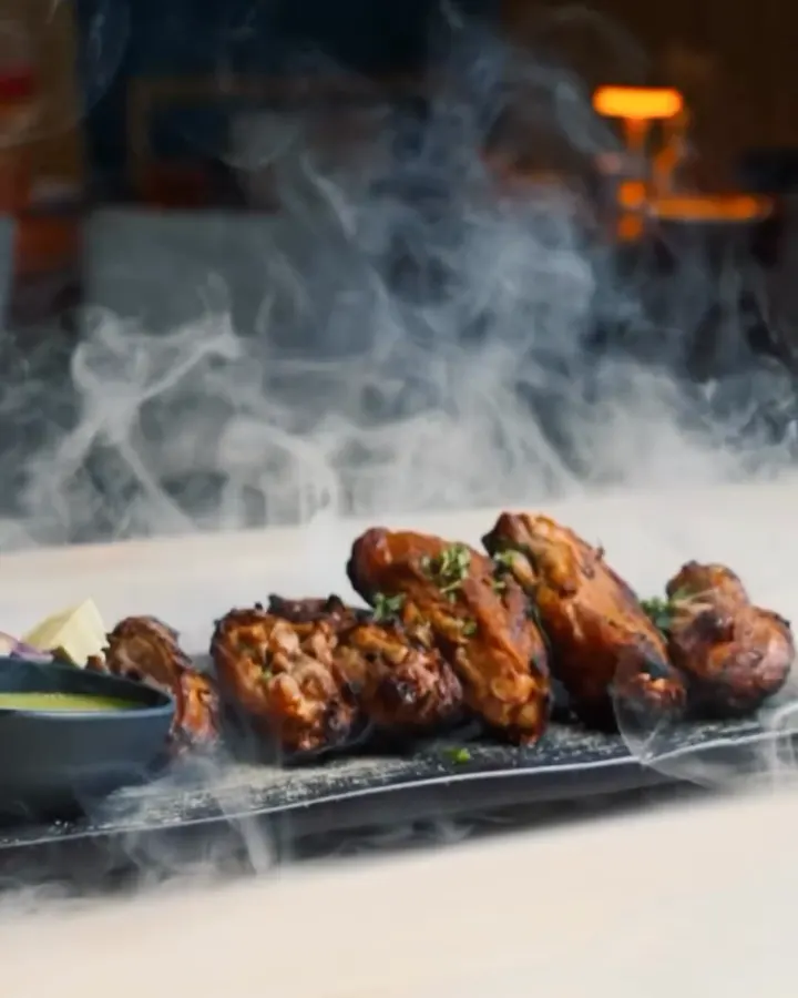 Grilled chicken served under a cloud of smoke