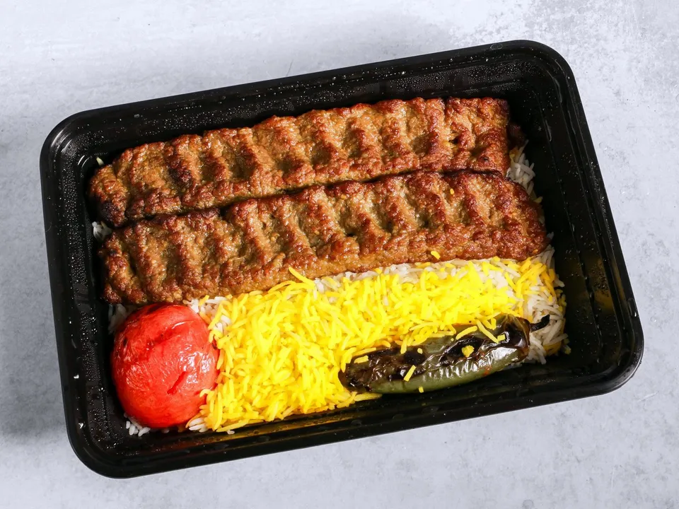 Two beef koobideh skewers with saffron rice, a grilled tomato and a pepper