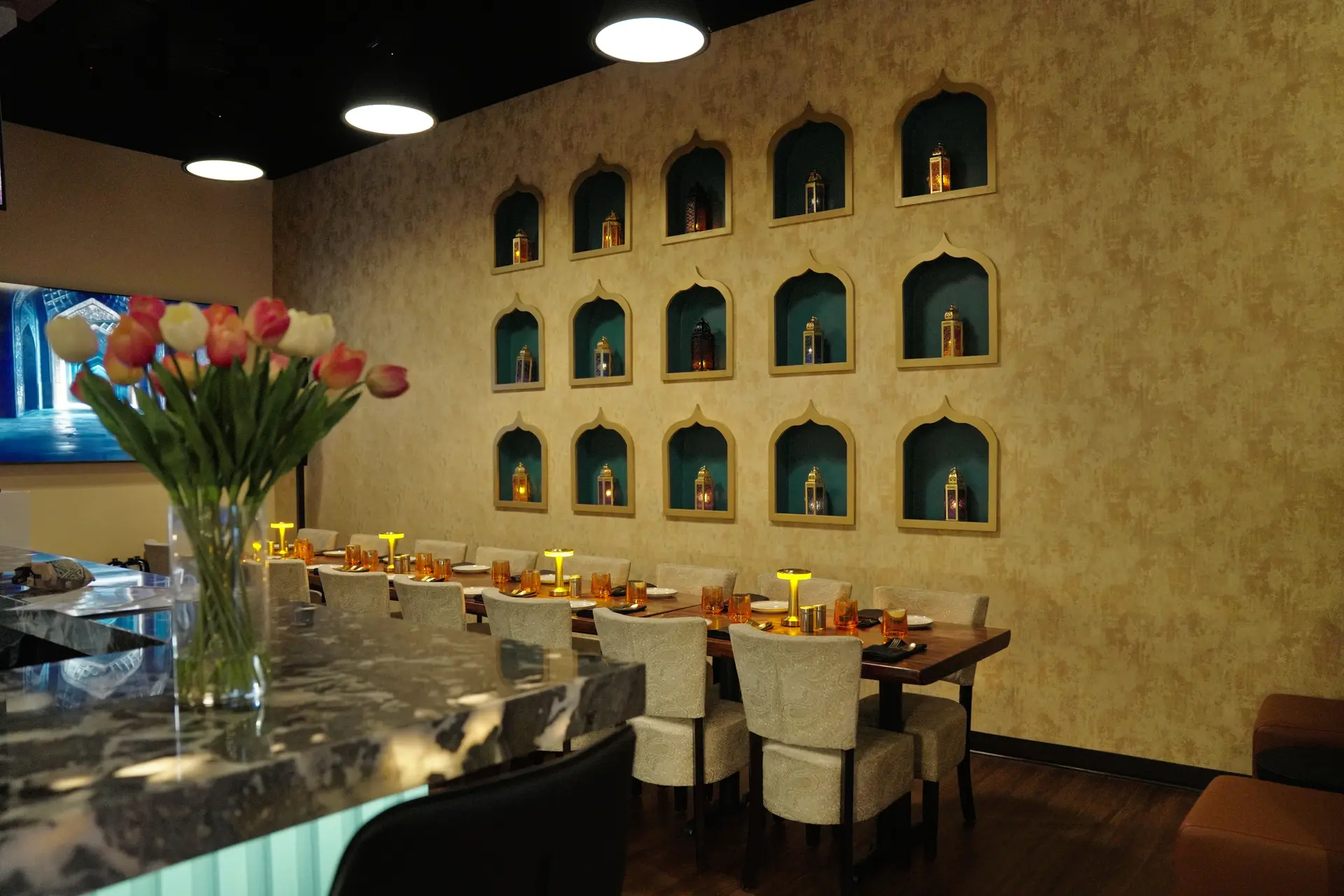 The long table under the lamp-lit plaster niches