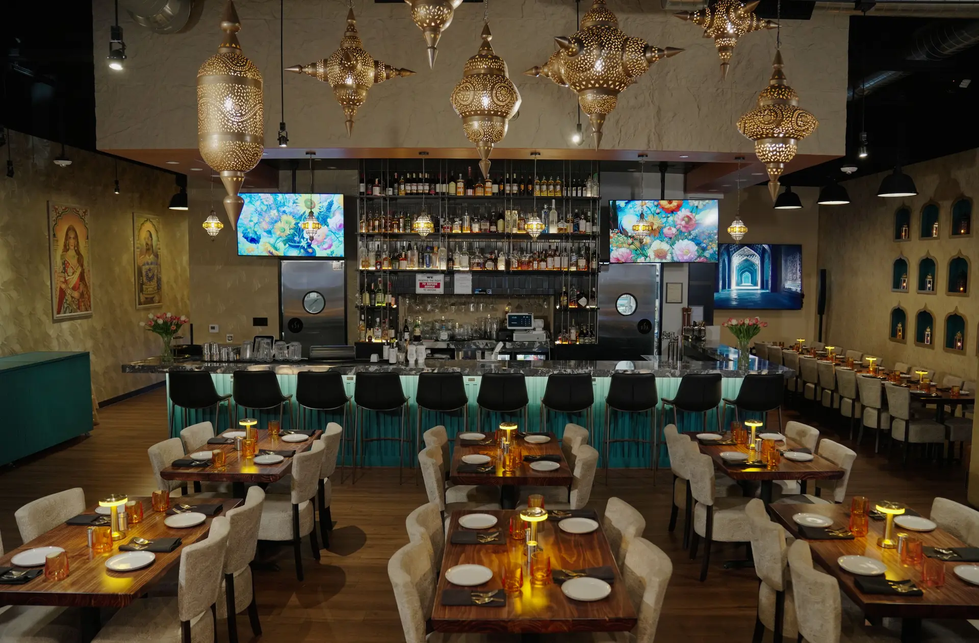 The Kebab & Kurry dining room set for dinner under brass lanterns, the bar lit teal