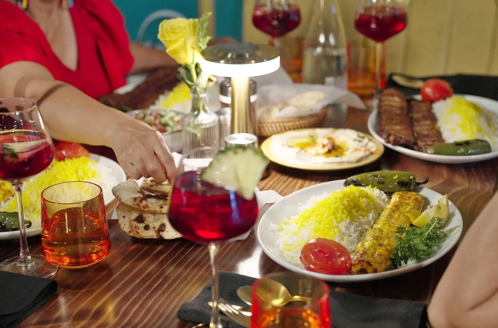 Plates of kebab, saffron rice and hummus shared across a table with sangria